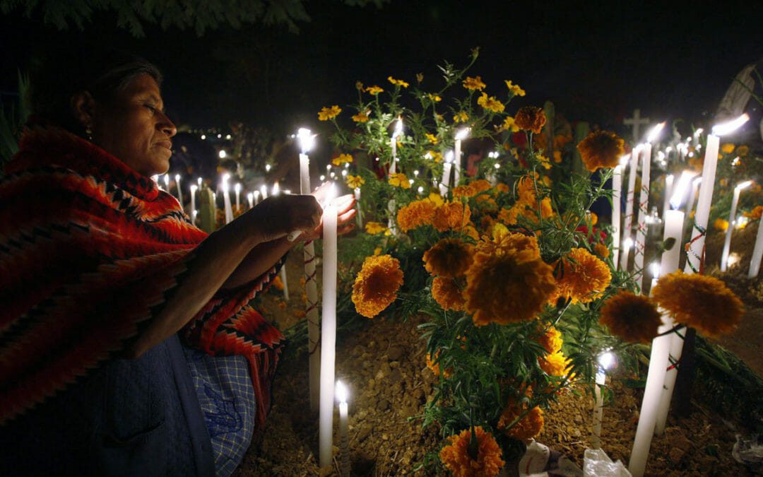 A woman lights a candle on a grave at a cemetery in Oaxaca November 1, 2010. Mexicans are celebrating the Day of the Dead paying homage to their dead relatives by preparing meals and decorating their graves. The Day of the Dead festival has its origins in a pre-Hispanic Aztec belief that the dead return to Earth one day each year to visit their loved ones.